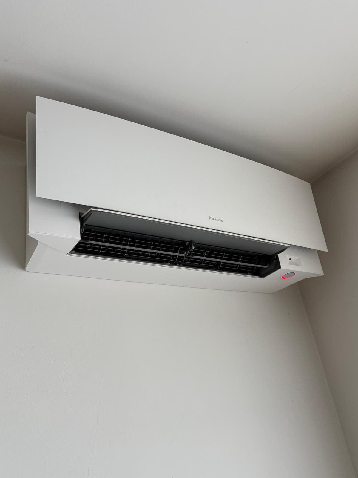 Weiße Daikin Inneneinheit oben an der Wand montiert, mit geöffneter Luftklappe