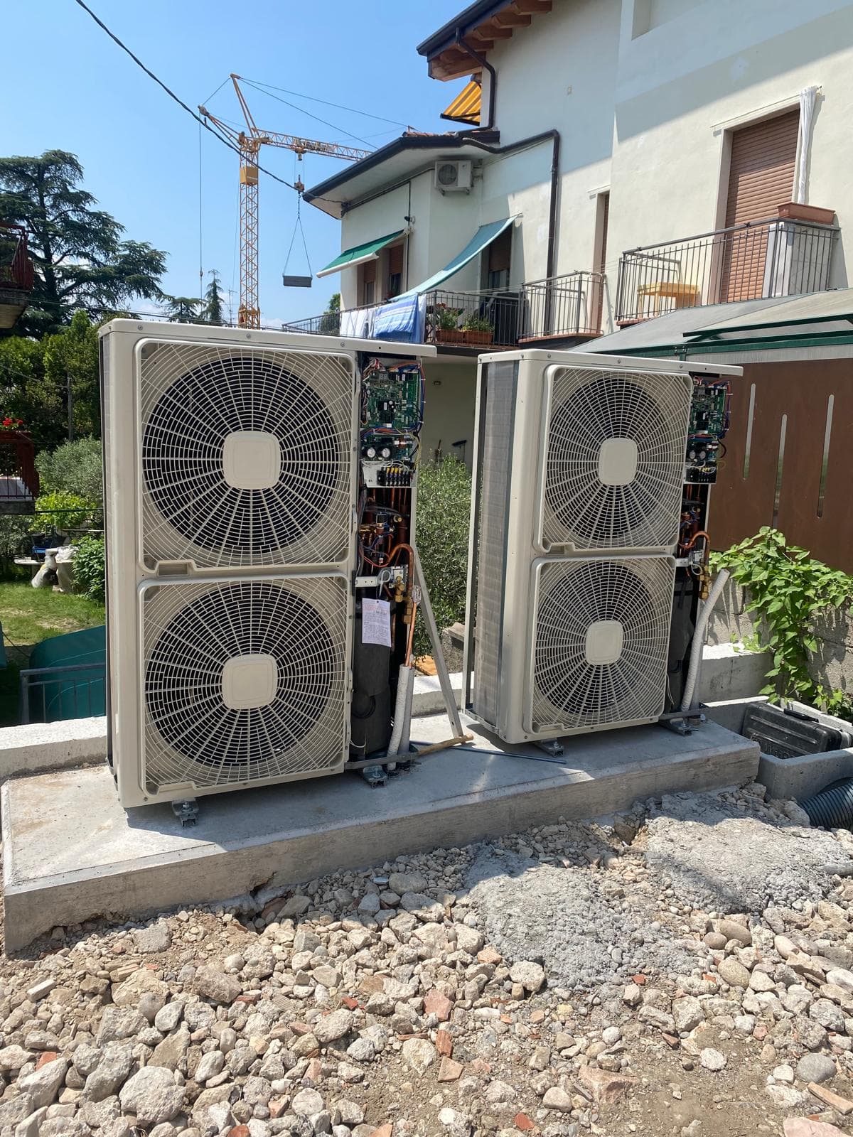 Zwei nebeneinander stehende Außeneinheiten mit je zwei Ventilatoren auf einem Betonsockel, mit geöffneten Revisionsklappen während der Installation